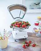 Strawberries on retro kitchen scales and rustic wooden table