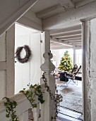 Vintage stairwell decorated with ivy and wreath and view of Christmas tree in living area