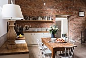Rustic wooden table in open-plan kitchen with brick wall
