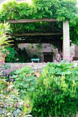 View across flower bed to pergola covered with wisteria