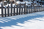 Wooden garden fence in snow
