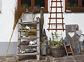 Ladder, bird cage, basket, broom and various natural finds against house façade