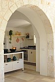 View through traditional arched doorway into modern country-house kitchen