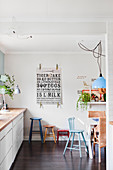 Colourful stools in white kitchen with dark wooden floor