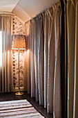 Floor-length curtains screening dressing room and standard lamp in bedroom