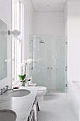 All-white bathroom with high ceiling and shower in the alcove
