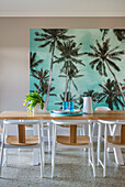 Bright dining room with palm tree mural and wooden table