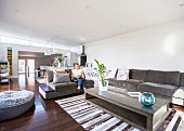 Open living area with upholstered furniture and matching coffee table, woman sitting on sofa