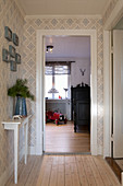 View along hallway with patterned wallpaper into child's bedroom with antique bed