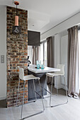 Two modern bar stools at kitchen counter next to brick wall