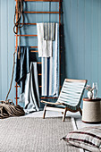Wooden frame as a towel holder, in front of it a beach chair and wooden side table with rope covering