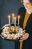 Frau hält DIY-Adventskranz aus Stoffresten, mit vier brennenden Kerzen