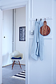 Towel and wooden board hung from pegs and classic chair in background