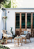 Wicker chairs in front of old glass doors on the sunny courtyard terrace