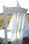 Fringed garland made from strips of fabric on back of chair outside