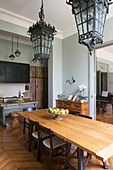 Antique lamps above dining table in front of open-plan kitchen