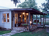 Bicycle leaning against illuminated veranda of wooden cabin