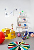 Kinderzimmer mit gelber Kunststoff-Schulbank, buntem Spielzeug, blauem Dreirad und weißem Regal