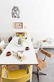 Verschiedene Stühle um den weißen Tisch mit Kuchen und Kaffeetassen