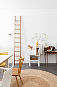 Ladder leaning against wall in dining room with high ceiling and white walls