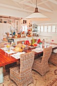Wicker chairs around set dining table in open-plan country-house kitchen