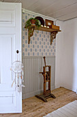 Old wooden tool below shelf on wall with wainscoting and patterned wallpaper