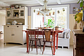 Red table with chairs and bench in Scandinavian country-house kitchen
