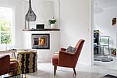 Red velvet armchairs in front of corner fireplace in white living room