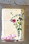 Delicate rose and lavender flowers in vase on windowsill