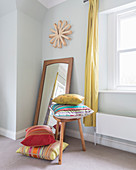 Brightly striped cushions on and next to stool in front of mirror