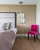 Hot-pink upholstered chair next to bed with upholstered headboard