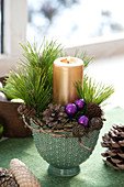 Small candle arrangement with pinus twigs and golden candle