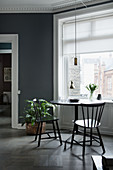 Black table and two chairs below window in grey wall