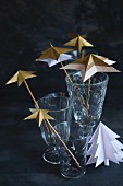 Arrangement of paper stars threaded on rods in glasses on table