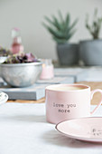 Pink cup with lettering on set table