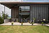 Lawn and terrace outside modern house with dark façade