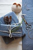 Gifts wrapped in blue fabric tied with parcel string and decorated with larch cones