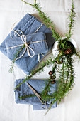 Larch twigs in white jug and gifts wrapped in blue fabric