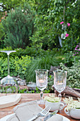 Tealights in wine glasses on set table in garden