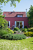 Rotes Haus im naturnahen Sommergarten mit Blumenwiese