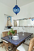 Mediterranean mosaic table and wicker chairs below large mirror on wall
