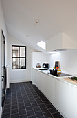 White fitted kitchen with black floor tiles