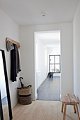 Mirror, wooden bench and coat pegs in hallway