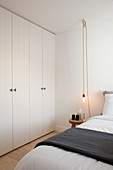 Fitted wardrobes, double bed, stool used as bedside table and pendant lamp in bedroom