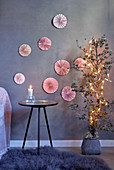 Rosafarbene Papierrosetten an grauer Wand als Weihnachtsdeko