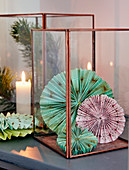 Christmas arrangement of rosettes made from patterned paper in candle lantern