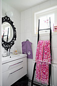 Shower stall and ladder used as towel rail in white bathroom