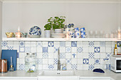 White and blue wall tiles and shelf above sink in kitchen