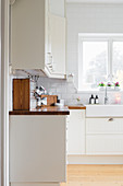weiße Einbauküche mit Fliesenwand und Fenster