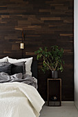 Zimmerpflanze auf dem Nachttisch vor mit Holz verkleideter Wand